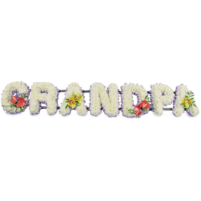 In this personalised funeral tribute, the word "GRANDPA" is presented in large, block-style letters arranged horizontally, each one densely covered in white chrysanthemums. The flowers are placed so closely that no gaps are visible, creating a plush, textured surface that feels both gentle and reassuring, like a floral embrace. Their bright white petals convey purity, peace, and a sense of calm, qualities often sought at a funeral or memorial. Around the base of each letter, a narrow edge of soft lavender ribbon shows beneath the blooms, tracing a delicate lilac line that helps define the shapes and adds an understated touch of colour and refinement. The entire composition is supported by dark green bars that run discreetly behind the letters, ensuring the tribute can be positioned securely at a service in Yiewsley, perhaps near the churchyard or a quiet corner of the crematorium. Four floral sprays bring vivid colour to the design. On the far-left G, a cluster of deep red anthuriums stands out, their glossy, heart-shaped spathes and cheerful yellow spadices framed by lush green foliage and small filler flowers. The first A is adorned with yellow-green orchids, their elegant, arching petals and patterned throats hinting at exotic beauty and enduring remembrance. The D repeats the dramatic red anthurium motif, echoing the emotion expressed at the start of the tribute, while the final A mirrors the first with another delicate arrangement of lime-toned orchids. Lovingly arranged by Yiewsley Florist, this "GRANDPA" tribute offers a beautiful, bespoke way to say goodbye, sharing love, gratitude, and cherished memories in a language of flowers.