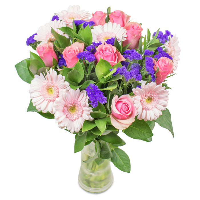 This thoughtfully arranged floral bouquet from Yiewsley Florist features a harmonious blend of around seven to nine pink roses, each petal displaying gentle gradients from blush to medium pink, spiralling in timeless elegance-some just unfurling, others in bud. Intermingled are five to seven pale pink gerbera daisies, their faces broad and welcoming, centres tinged with soft cream. Accents of vivid purple statice bloom between, lending vibrant textural contrast and striking depth. Lush green foliage surrounds the bouquet, each leaf glossy and robust, echoing the greenery seen near Yiewsley's Stockley Park. The clear glass vase displays the stems tidy and fresh, water shimmering below, enhancing the impression of a just-picked arrangement. Set against a white background, the colours feel crisp and lively, making the bouquet ideal for occasions from birthdays to anniversaries, Mother's Day surprises, or as a radiant accent in a home or office along Falling Lane-conveying feelings of happiness, gratitude, and affection with every carefully chosen bloom.