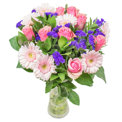 This thoughtfully arranged floral bouquet from Yiewsley Florist features a harmonious blend of around seven to nine pink roses, each petal displaying gentle gradients from blush to medium pink, spiralling in timeless elegance-some just unfurling, others in bud. Intermingled are five to seven pale pink gerbera daisies, their faces broad and welcoming, centres tinged with soft cream. Accents of vivid purple statice bloom between, lending vibrant textural contrast and striking depth. Lush green foliage surrounds the bouquet, each leaf glossy and robust, echoing the greenery seen near Yiewsley's Stockley Park. The clear glass vase displays the stems tidy and fresh, water shimmering below, enhancing the impression of a just-picked arrangement. Set against a white background, the colours feel crisp and lively, making the bouquet ideal for occasions from birthdays to anniversaries, Mother's Day surprises, or as a radiant accent in a home or office along Falling Lane-conveying feelings of happiness, gratitude, and affection with every carefully chosen bloom.
